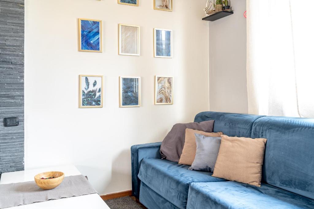 um sofá azul numa sala de estar com fotografias na parede em La casa di Vittoria em Arona