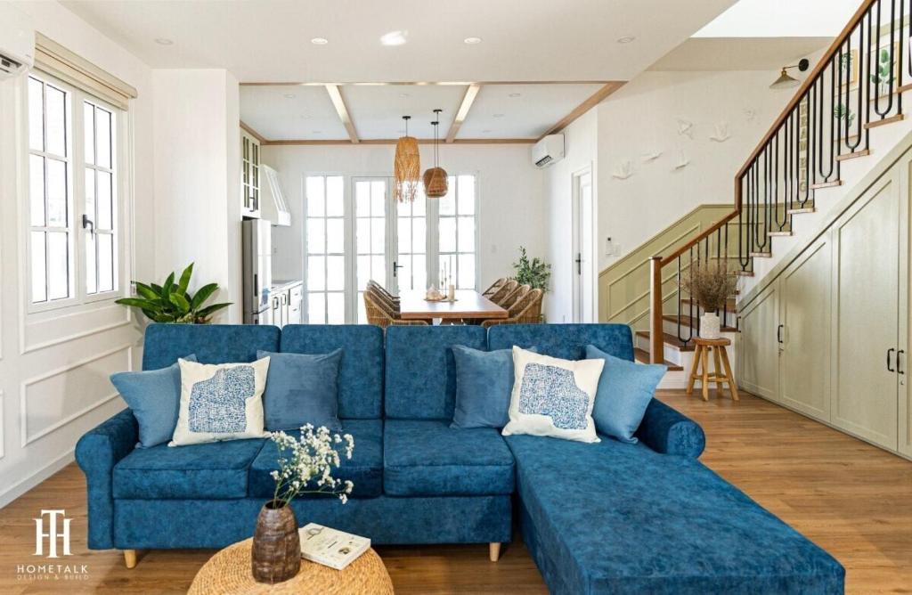 a living room with a blue couch and a staircase at Villa 3PN Novaworld Phan Thiết in Phan Thiet