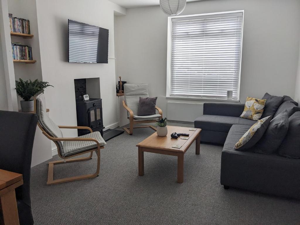 ein Wohnzimmer mit Sofa, Stühlen und einem Tisch in der Unterkunft Cape Cottage in Glyncorrwg