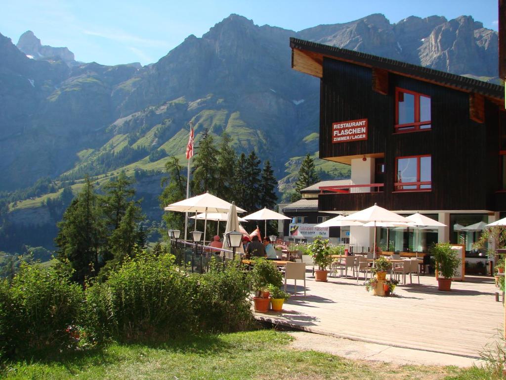 a restaurant with tables and umbrellas in front of mountains at Hotel Restaurant Flaschen in Albinen
