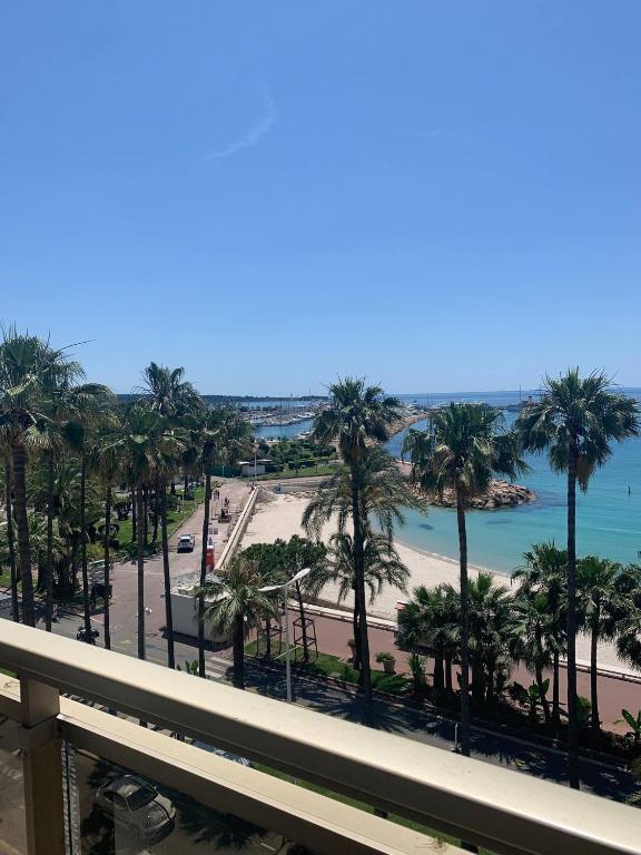 d'un balcon avec vue sur la plage et les palmiers. dans l'établissement Ô Béatrice Croisette, à Cannes