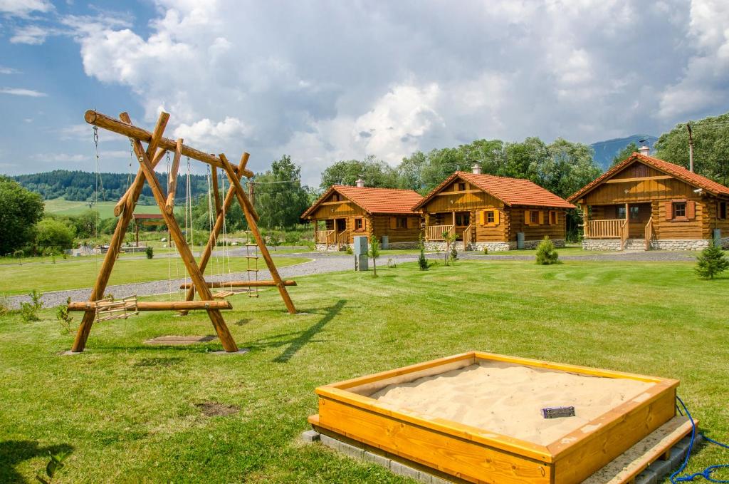 a park with a wooden swing set in the grass at Drevenice TriMount in Liptovský Mikuláš