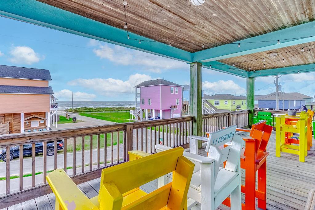 a deck with colorful chairs and a view of the ocean at Cozy Beach Cabin - Beautiful Coast Views in Crystal Beach