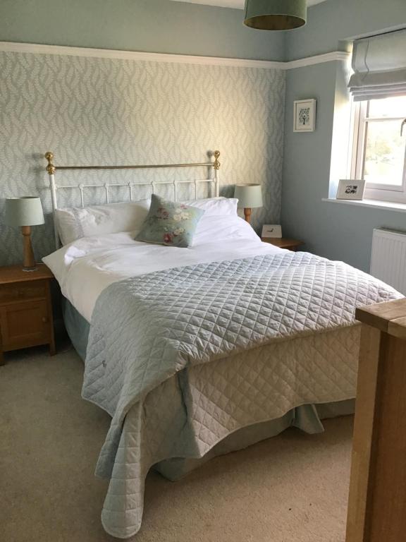 a bedroom with a large bed with white sheets and a window at A place to stay in Stoke Gifford in Bristol
