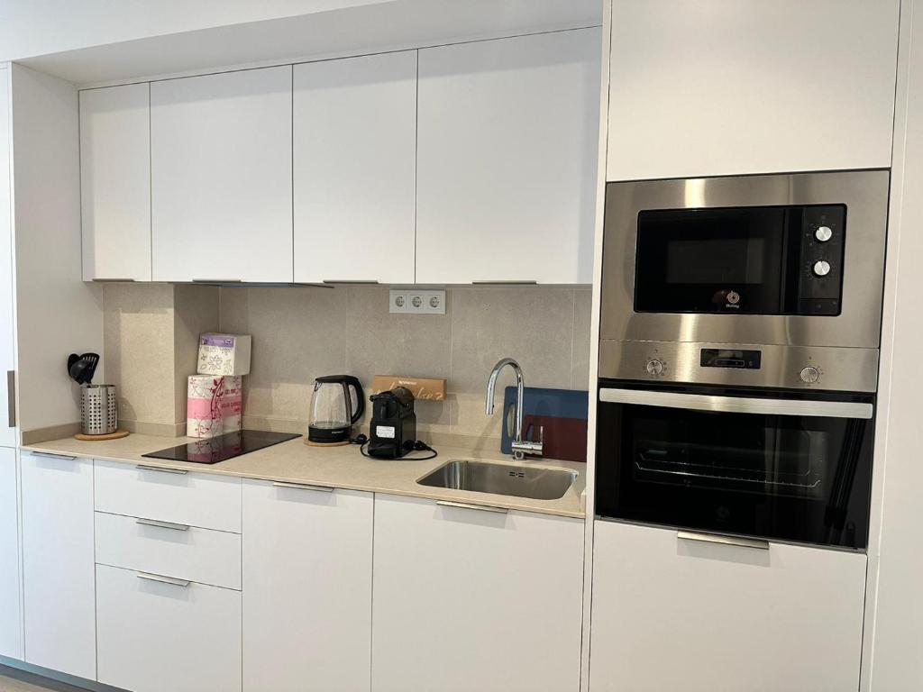 a white kitchen with a microwave and a sink at CASTILLA LUXURY B Apartments in Madrid