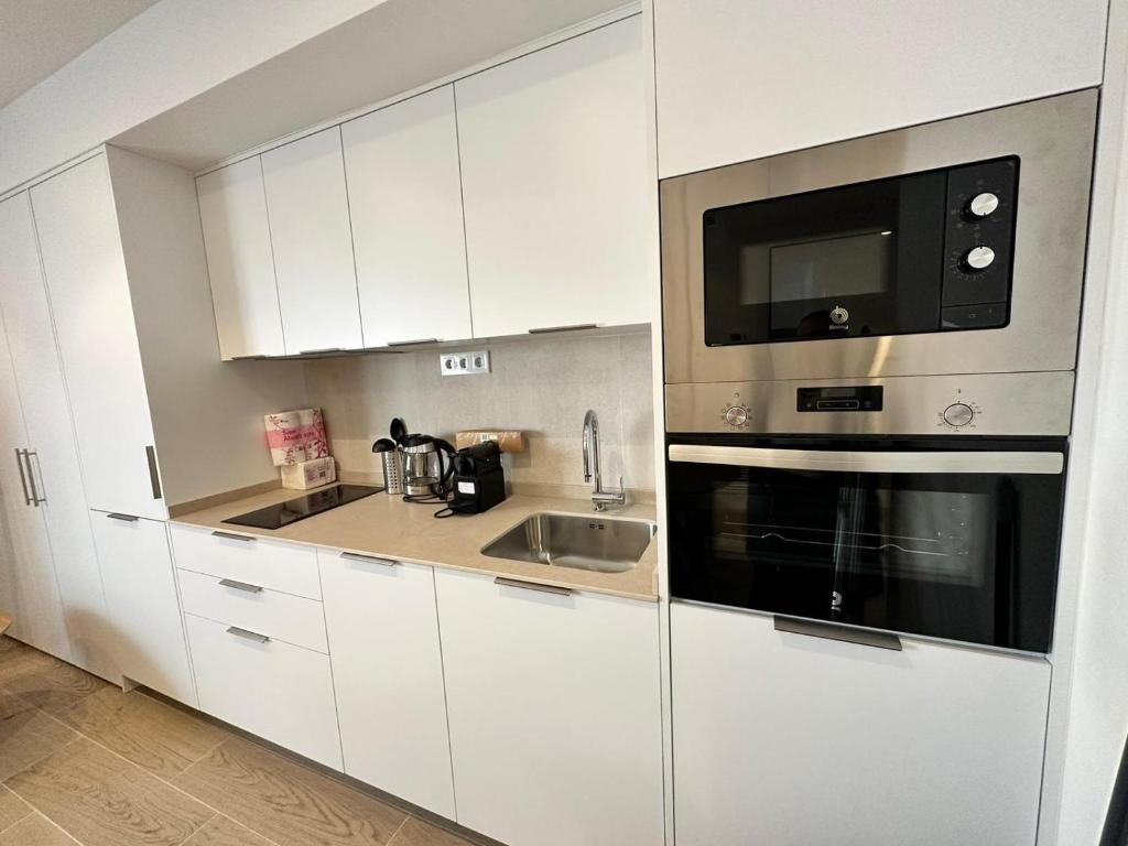 cocina blanca con fregadero y microondas en Castilla Luxury 2B Apartment, en Madrid