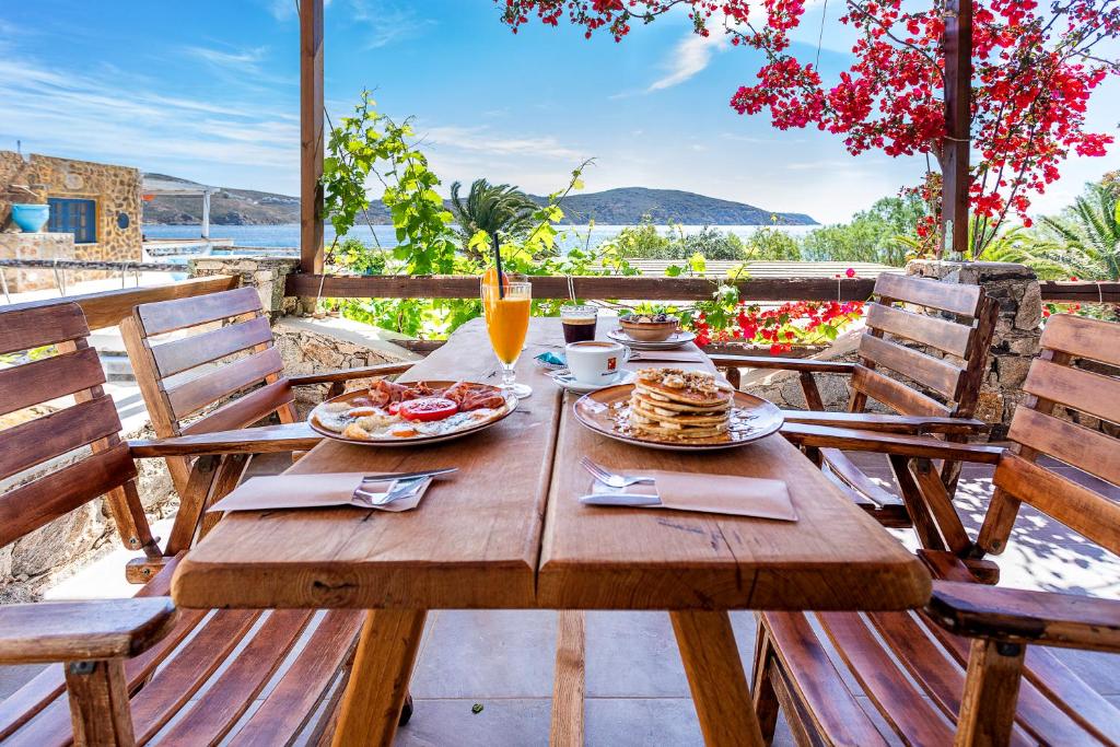 una mesa de madera con platos de comida en el patio en Vassilia on the beach Serifos, en Livadakia