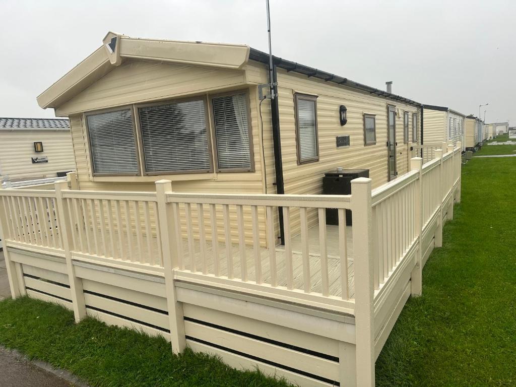 a yellow house with a white fence on a yard at Lyon’s Robin Hood Rhyl caravan sbw in Rhyl