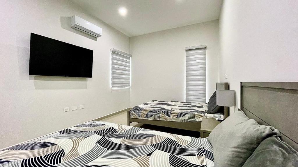 1 dormitorio con 2 camas y TV de pantalla plana en Sábalo Country, 2BDR Condo, en Mazatlán