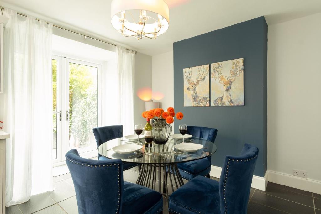 a dining room with a glass table and blue chairs at Stratford House in Leicester