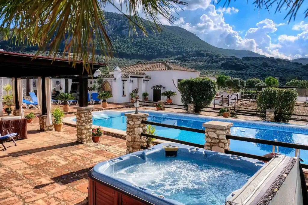 un patio trasero con bañera de hidromasaje y una casa en Pasa Fina, luxury holiday retreat, en Villanueva del Trabuco