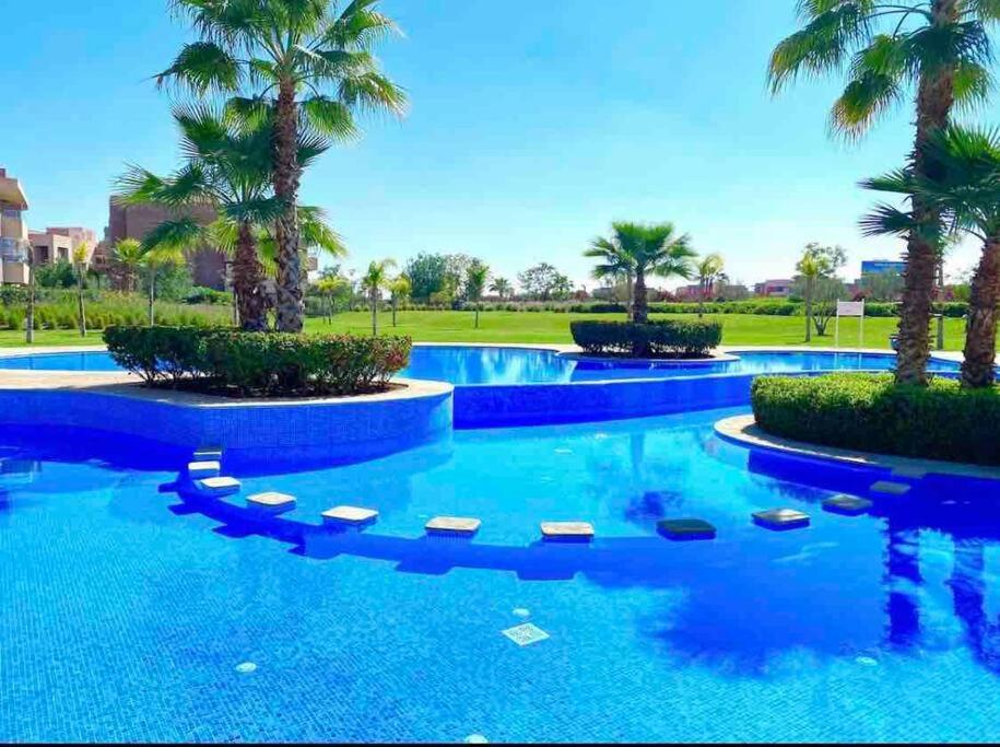 una grande piscina con palme e acqua blu di Appartement Prestigia Marrackech Golf City a Marrakech