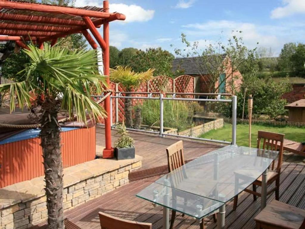 a patio with a glass table and chairs on a wooden deck at Tonga Cottage 302 Over Lane in Belper