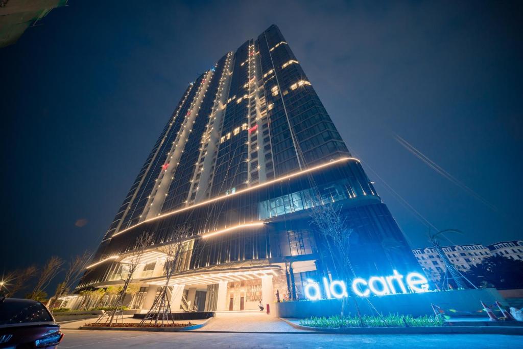 a tall building with lights on it at night at Căn hộ khách sạn Alacarte Hạ Long in Ha Long