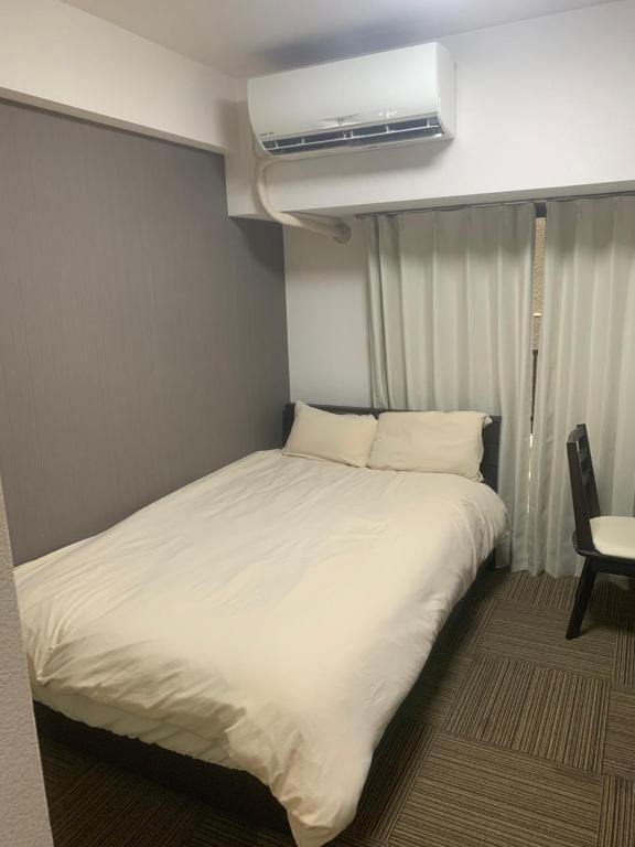 a bed in a small room with a air conditioner at LIONS YONEGAHAMA l 米が浜通 in Yokosuka