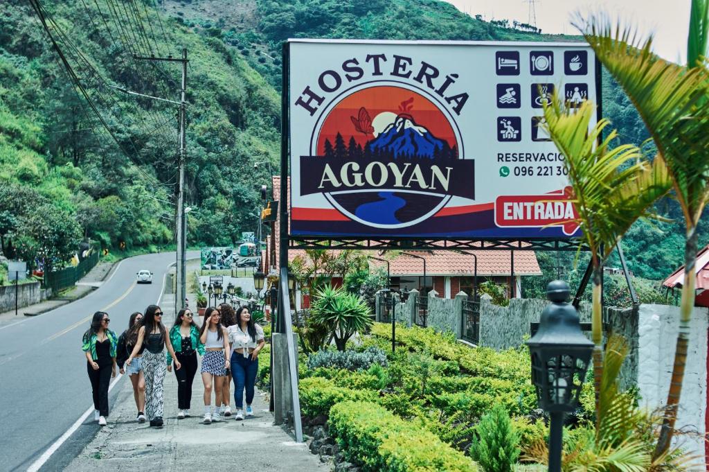 un grupo de personas caminando por una acera junto a una señal en Hosteria Agoyan, en Baños