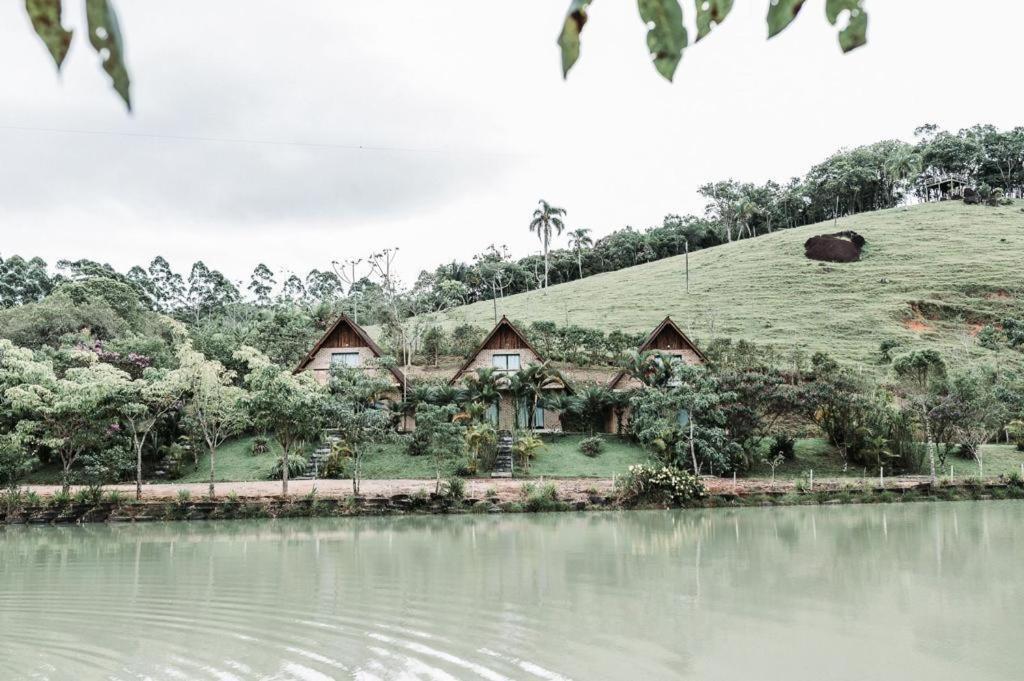 a house with a grassy hill next to a body of water at Fazenda Momm - Pousada e Eventos in Camboriú