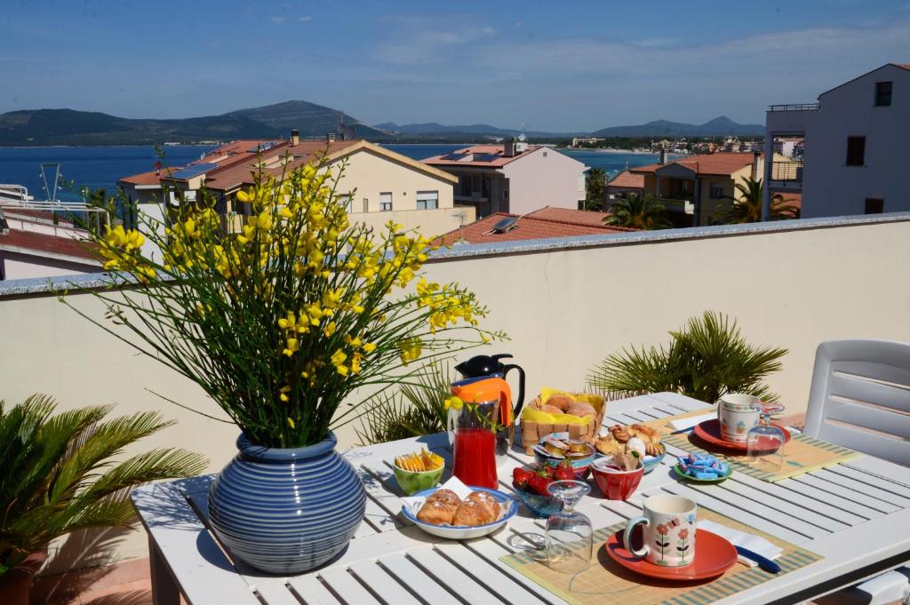 uma mesa com comida e um vaso na varanda em B&B Lloc D'Or em Alghero