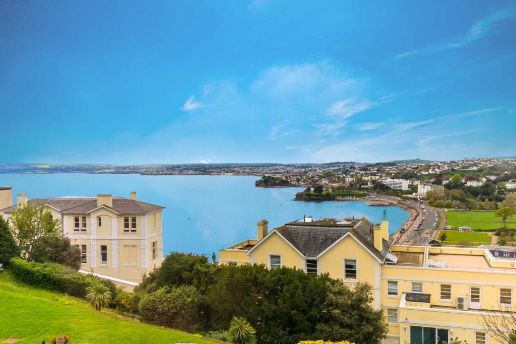 een uitzicht op een groot huis en een waterlichaam bij Stunning Sea View Central Torbay Home with Parking in Torquay