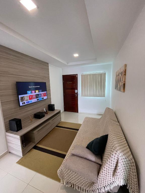 uma sala de estar com um sofá e uma televisão de ecrã plano em Apartamento Aconchego Carapibus em Conde