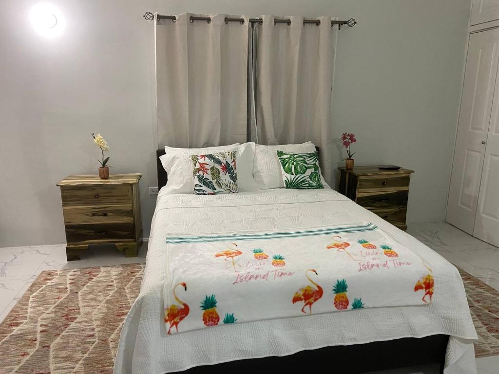 a bed with a white comforter with birds on it at MBS Travel Holistic Guest House in Mammee Bay