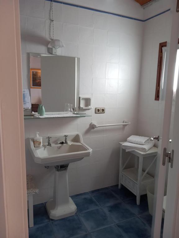 a white bathroom with a sink and a mirror at Cal Manyo in Puigvert de Lérida