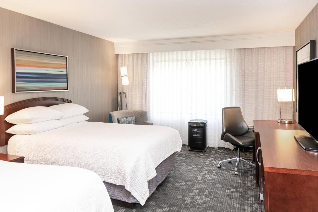 a hotel room with two beds and a desk at Courtyard by Marriott Columbus Tipton Lakes in Columbus