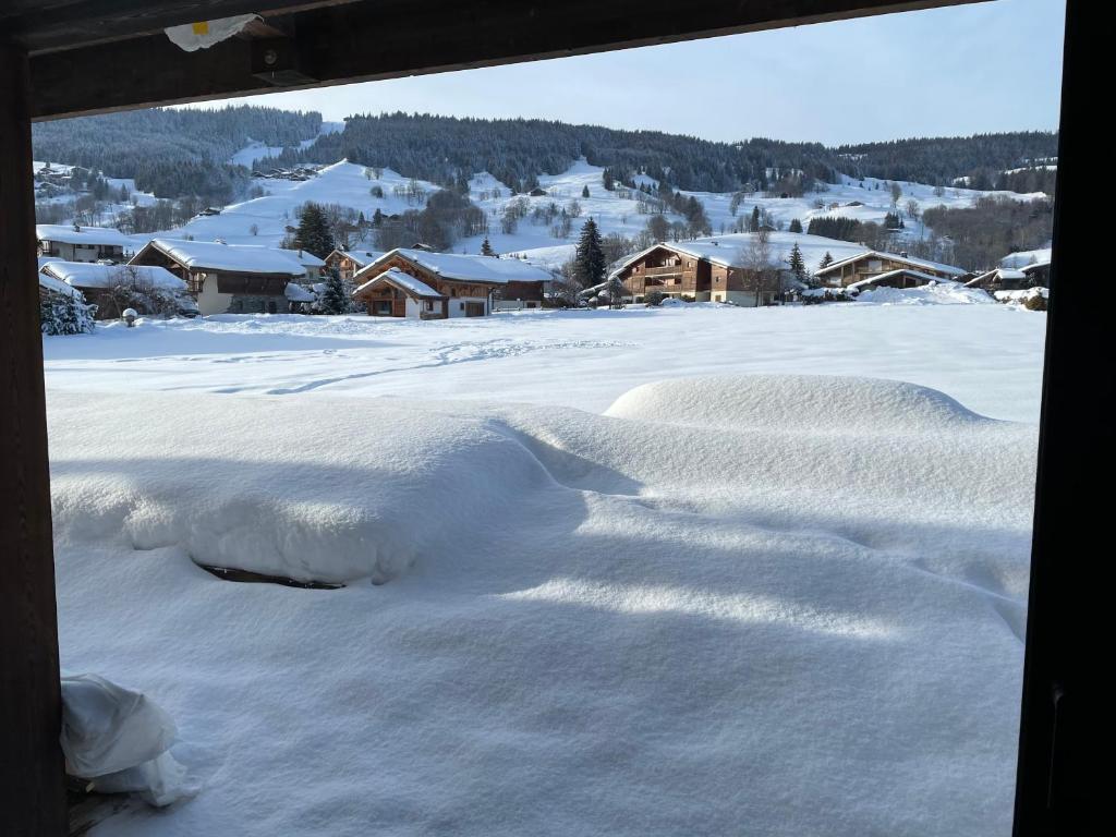 uma vista de um campo coberto de neve a partir de uma janela em Chalet Esquinade 4 bedrooms appartment Megève em Megève