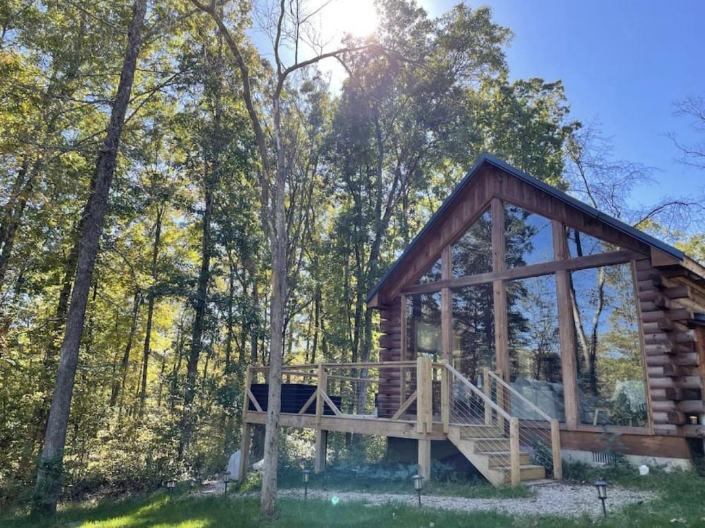 a log cabin with a deck in the woods at Fern Haven A modern take on Hocking Hills cabins in Stella