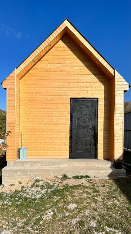 un bâtiment jaune avec une porte noire dans l'établissement Eldos_Kolsai, à Saty