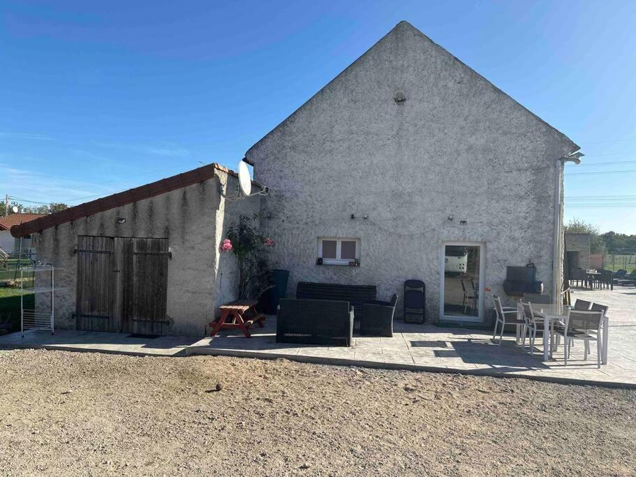 un grand bâtiment en pierre avec des chaises et une table dans l'établissement Rez de maison jardin appart, à Saint-Pont