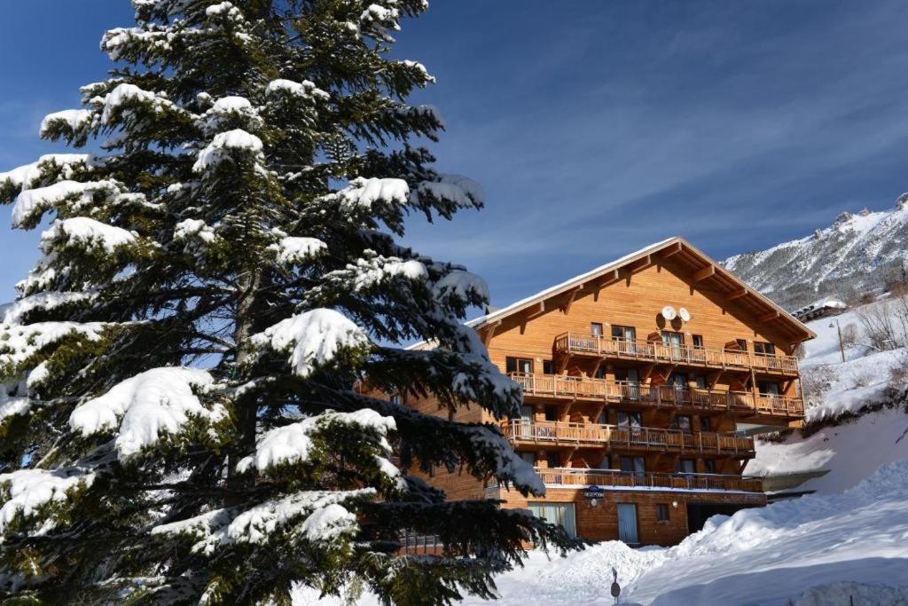 a ski lodge in the snow with a pine tree at Appartement sur les pistes de ski avec piscine in Sainte-Marie-de-Vars