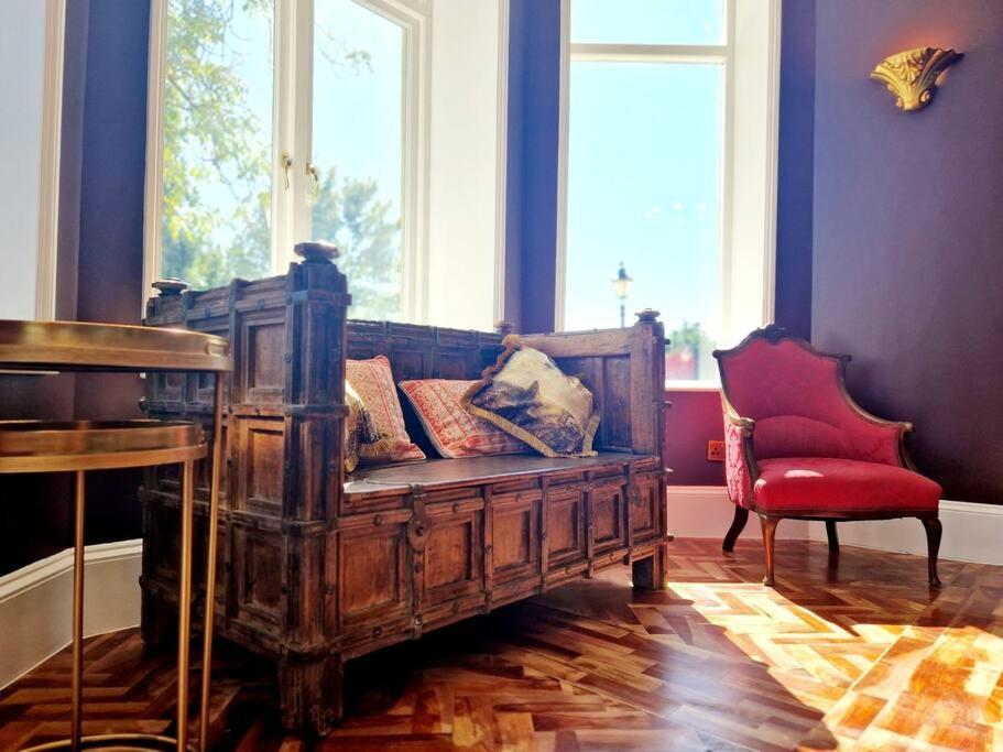 a living room with a wooden couch and a red chair at The Hamilton Luxury Let-The Duke in Scorton