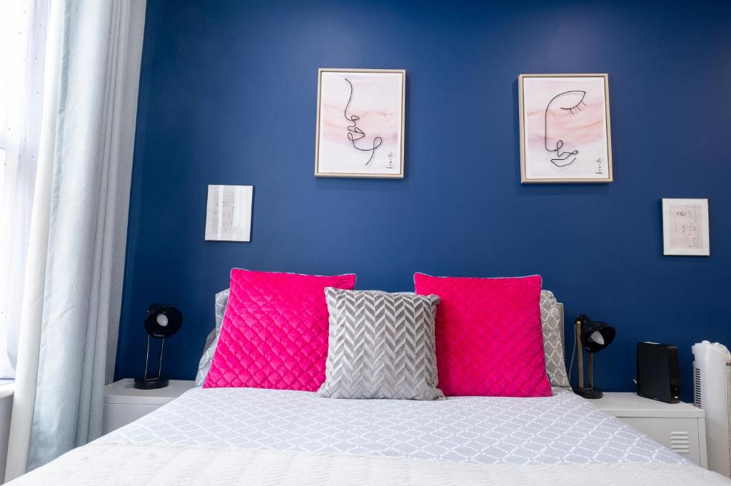 Schlafzimmer mit blauen Wänden und einem Bett mit rosa Kissen in der Unterkunft REEF9 - Modern central flat, 5 mins from beach, centre and Bournemouth International Centre in Bournemouth