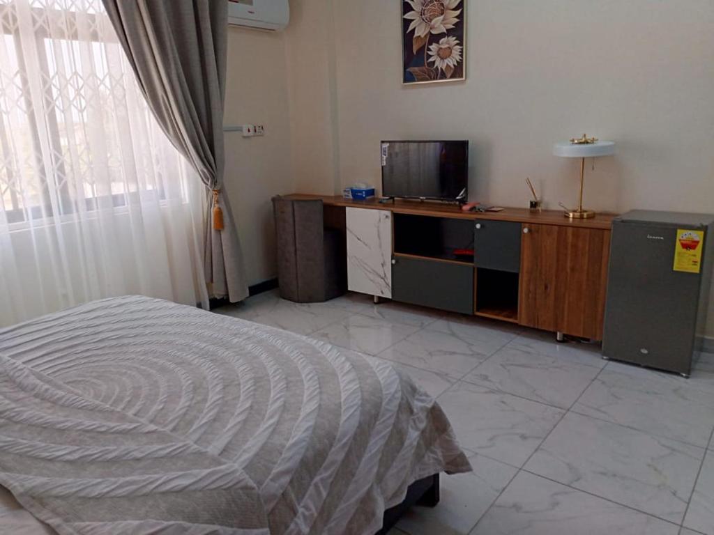 um quarto com uma cama e uma televisão em Edgard Hotel em Accra