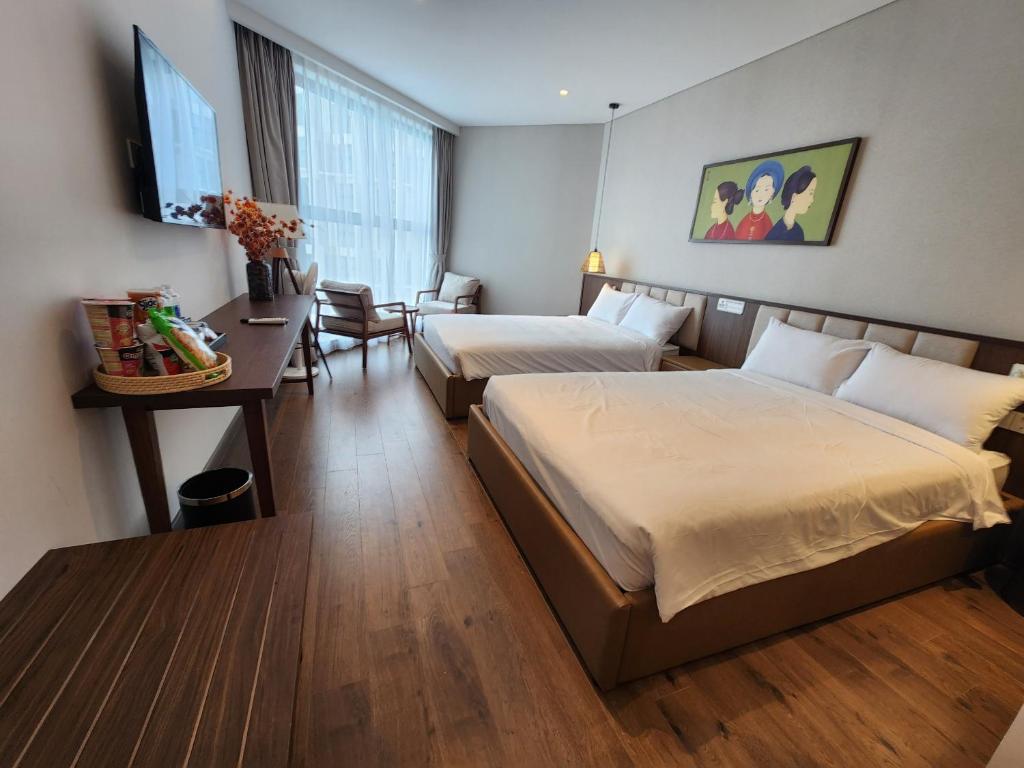 a hotel room with two beds and a desk at Apec Mandala Wyndham Mui Ne - V Ruby in Ấp Thiẹn Ái