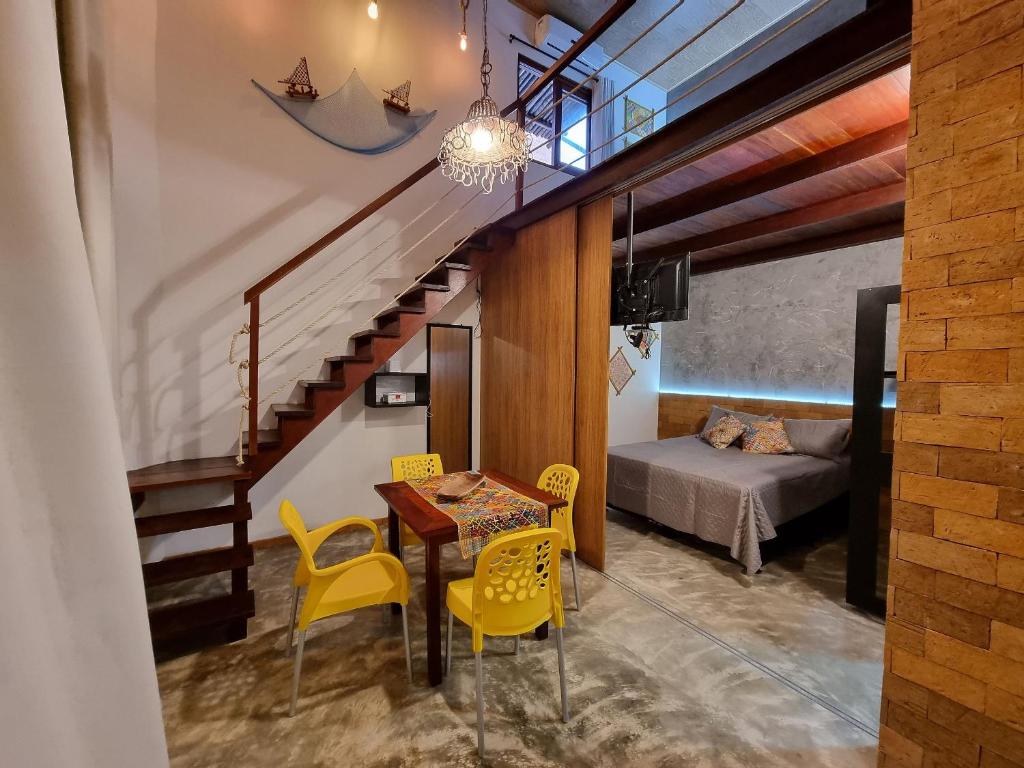 a room with a table and yellow chairs and a bed at Vila Manguezal, 2 suítes com opção de piscina e sauna integrada privativas na rota ecológica dos Milagres in Pôrto de Pedras