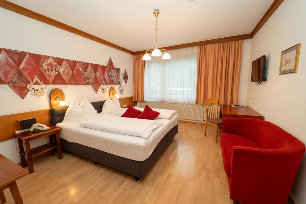 a hotel room with a bed and a red chair at Metzgerwirt in Radenthein