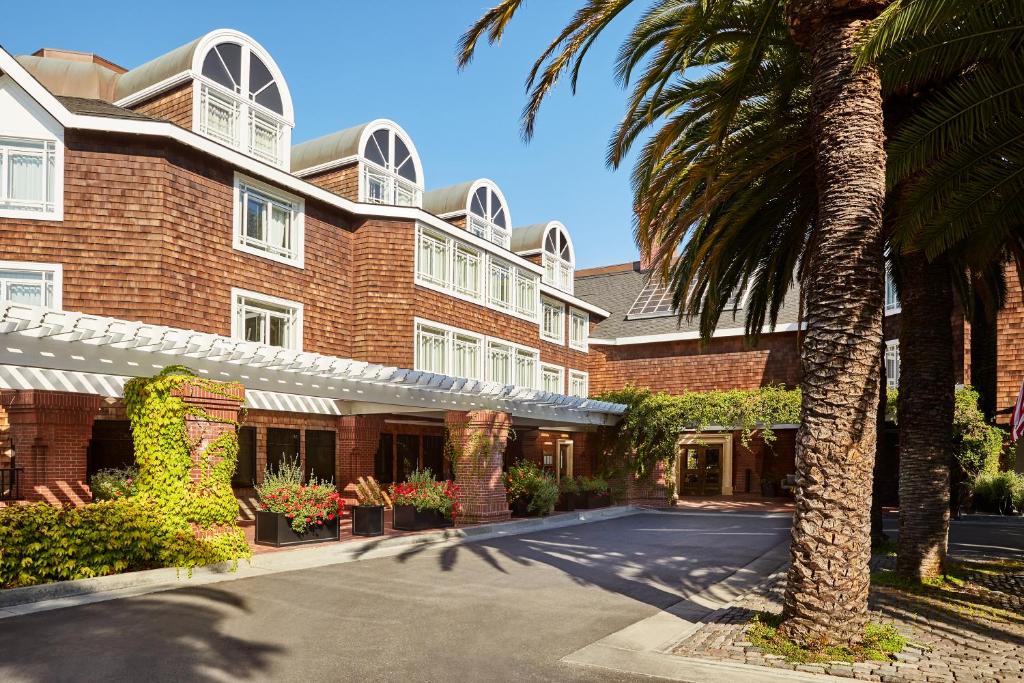 un edificio con una palmera delante de él en The Stanford Park Hotel en Menlo Park