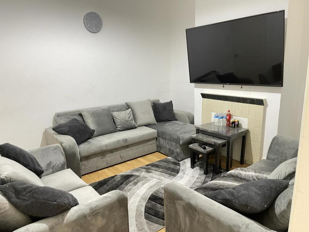 Hometel Large Luxurious Comfy Home Can Sleep 16 في Thornton Heath: غرفة معيشة مع أريكة وتلفزيون بشاشة مسطحة