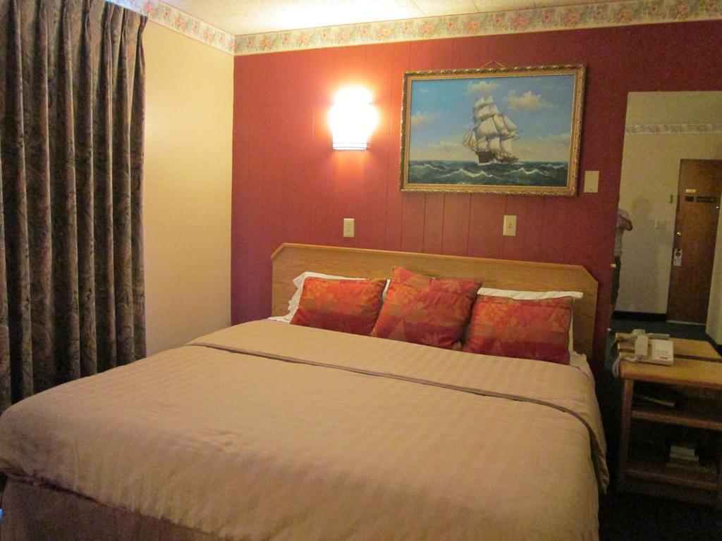 1 dormitorio con 1 cama grande y paredes rojas en Townhouse Motel, en Longview