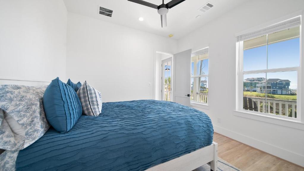 een slaapkamer met een bed met blauwe kussens en een raam bij Uncharted in Galveston
