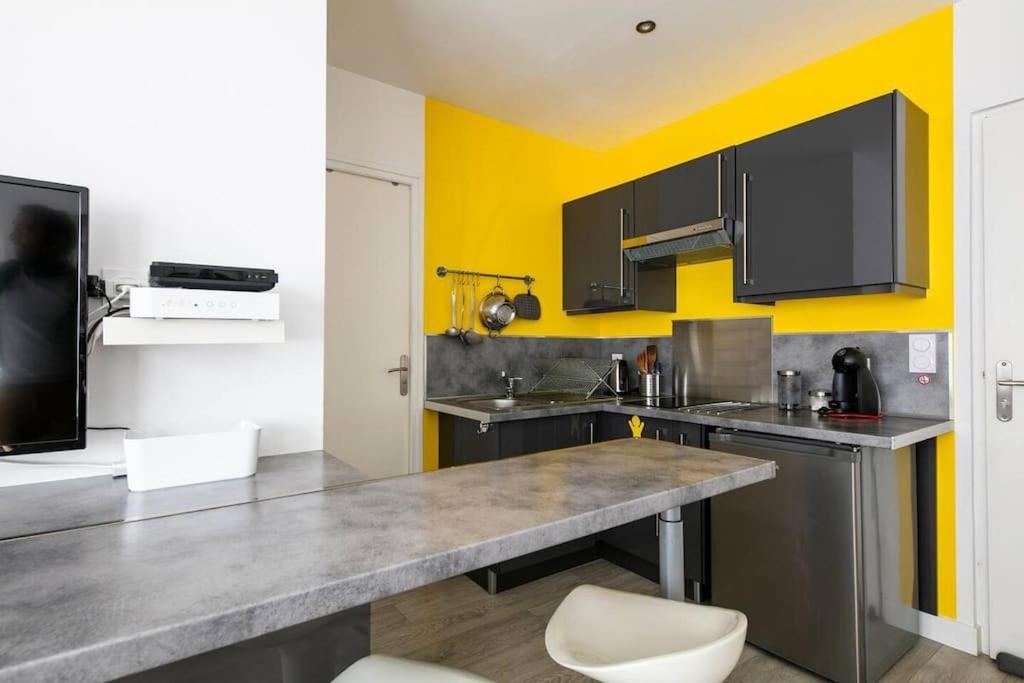 une cuisine avec un comptoir et un mur jaune dans l'établissement 600m Gare et 400m Gem: lit double, wifi fibre, à Grenoble