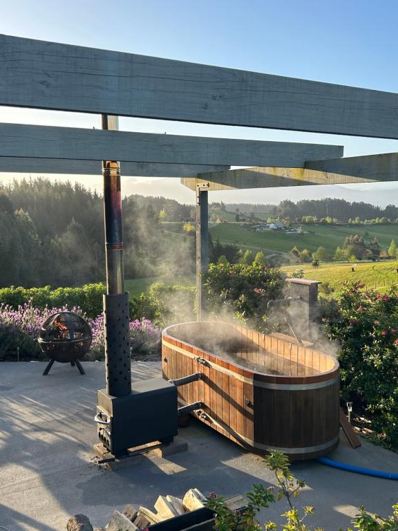 a hot tub on a patio with a grill at The shed with a view in Mahana