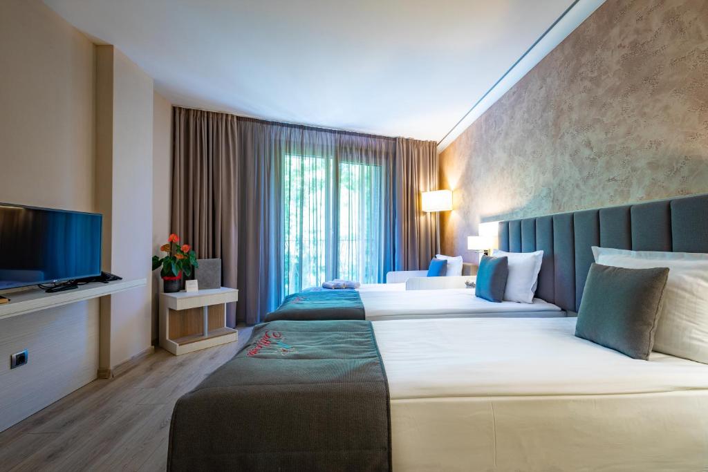 クルシュナにあるHotel & Relax Zone Cattleyaのベッド2台とテレビが備わるホテルルームです。