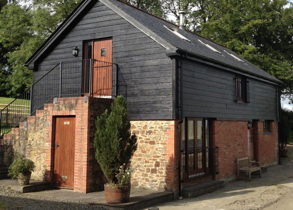ein kleines schwarzes Gebäude mit einer Tür und einem Baum in der Unterkunft Holsworthy Holiday Cottages in Holsworthy