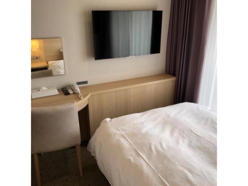 ein Hotelzimmer mit einem Bett und einem Schreibtisch mit einem TV in der Unterkunft Business INN Umesaki - Vacation STAY 63382v in Nagasu