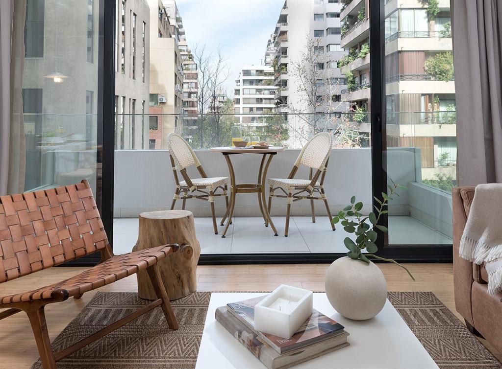 a living room with a table and chairs on a balcony at Zip Housing El Golf in Santiago
