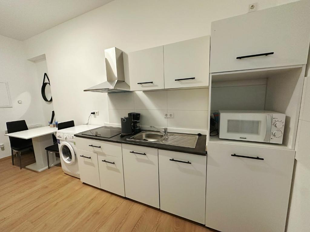 eine weiße Küche mit einer Spüle und einer Mikrowelle in der Unterkunft 2 schlafenzimmer Waschmaschine Eller in Düsseldorf