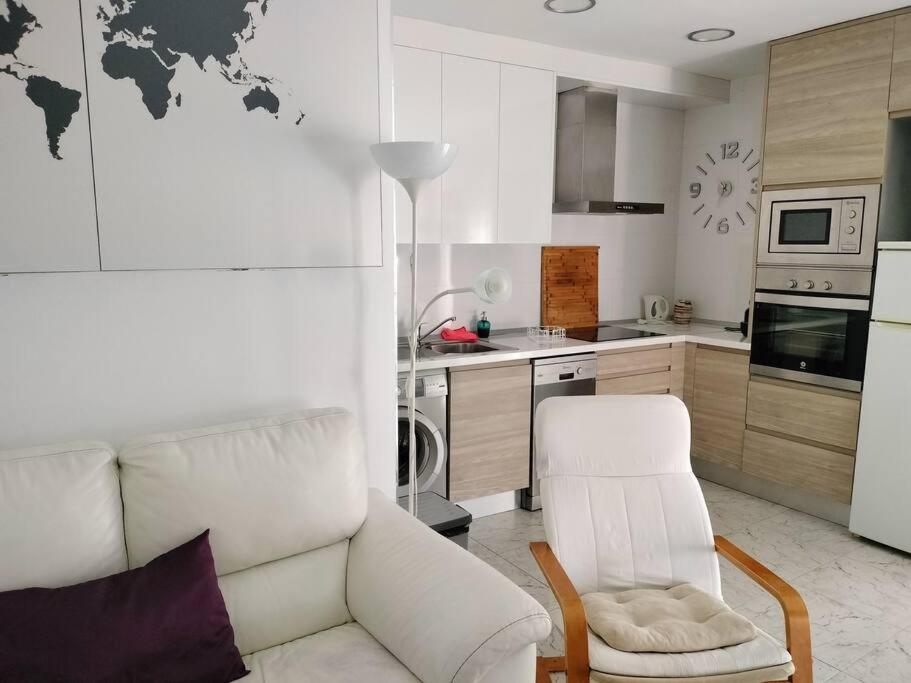 a living room with a white couch and a kitchen at Apartamento La Doncella in Alcalá de Henares